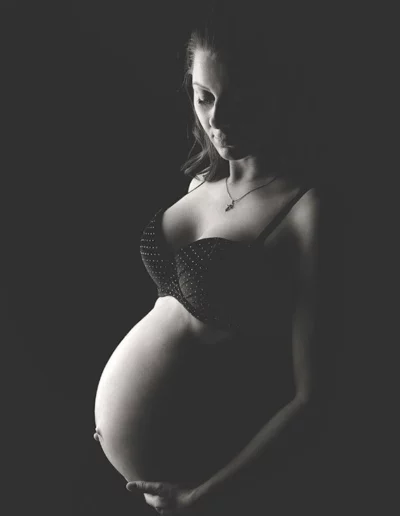 Schwarz-weiße Studioaufnahme eines Schwangerschaftsfotoshootings im Streiflicht