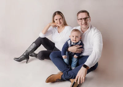 Glückliche Familie im Fotostudio vor einem sanften cremefarbenen Hintergrund.