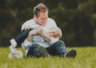 Fröhlicher Vater und kleiner Sohn, die auf der Wiese lachen und spielen